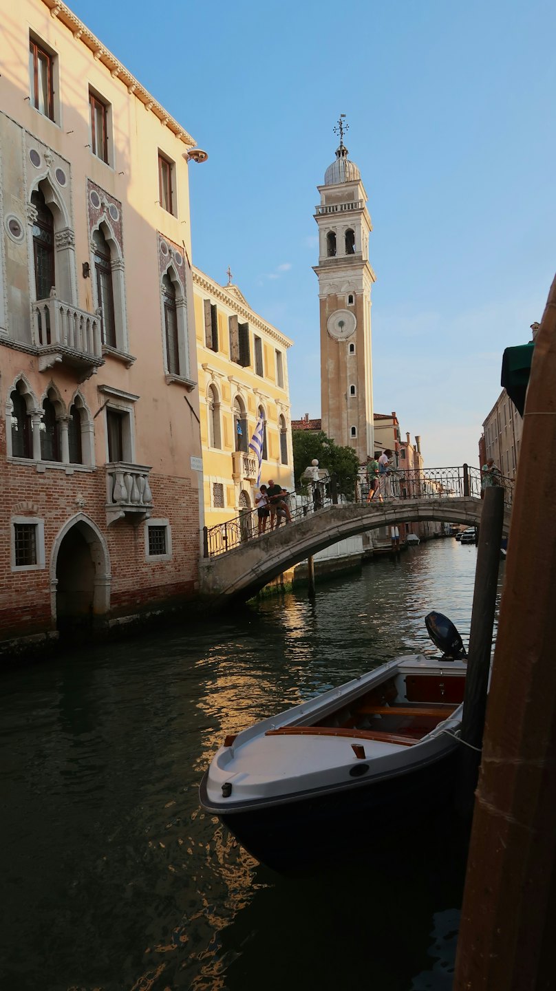 Canale veneziano con motoscafo ed edifici sotto un ponte.
